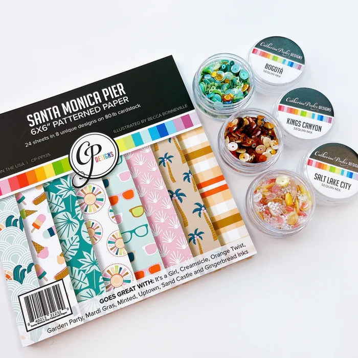 Catherine Pooler - Patterned Paper - Santa Monica Pier. This funky beach and boardwalk themed paper pack is full of summery patterns and seaside prints! From palm trees, waves, tropical leaves to a board short plaid and sunglasses, this pack has it all! Available at Embellish Away located in Bowmanville Ontario Canada.