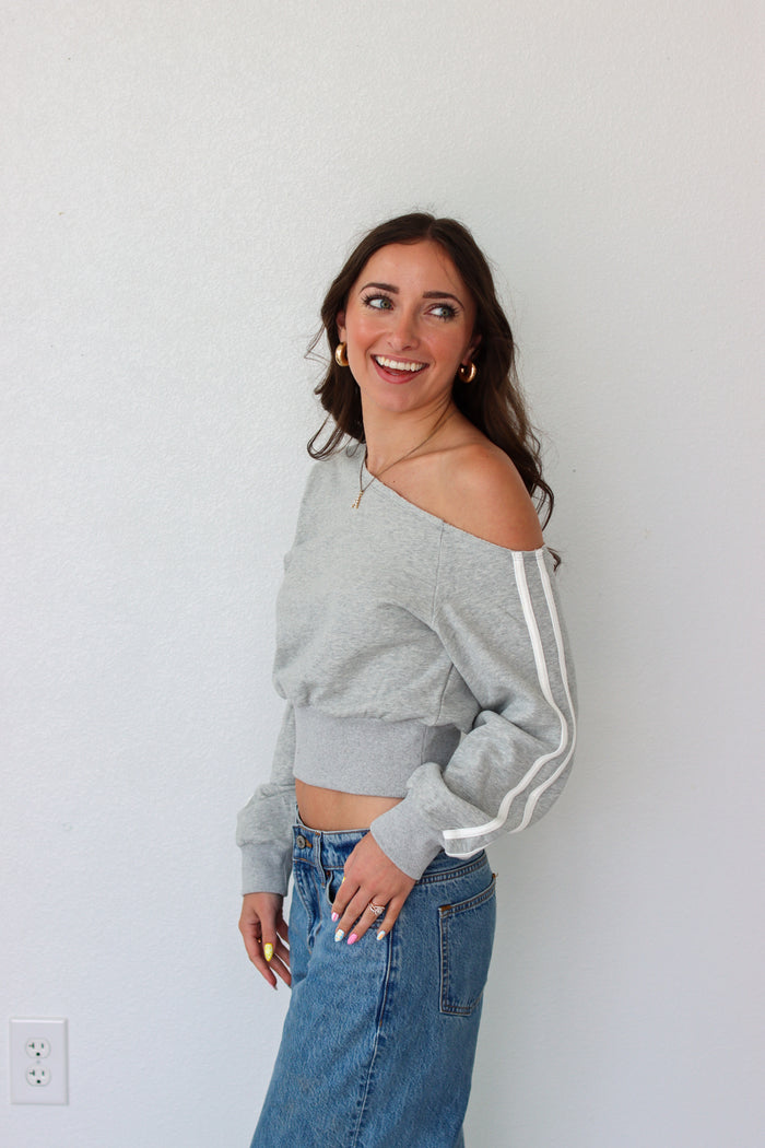 Woman wearing a light gray off the shoulder sweater top