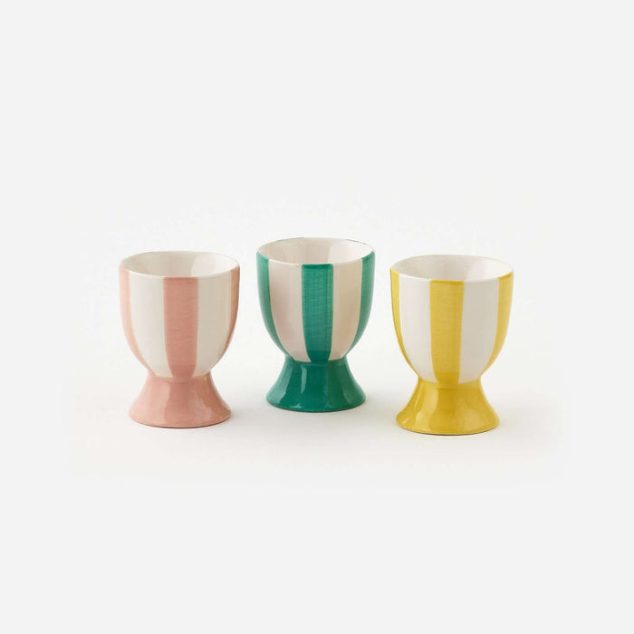 Three colorful egg cups with vertical stripes on a white background