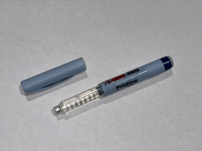 A gray insulin pen lies on a white surface; its cap is removed and rests nearby.