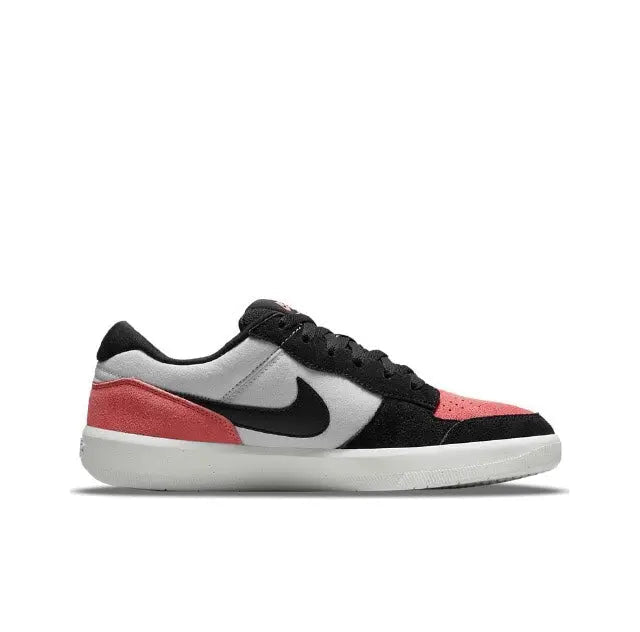 Low-top Nike SB sneakers with black uppers, white swoosh, and pink side panels