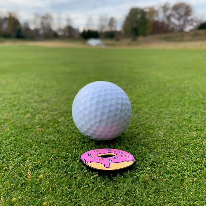 Kolorspun Pins Taco Magnetic Golf Ball Marker on a golf tee, featuring a colorful taco design for easy ball marking.