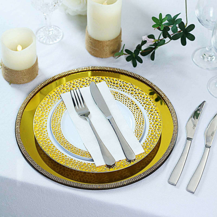 Elegant gold and white dinnerware set with cutlery on a beautifully styled table.