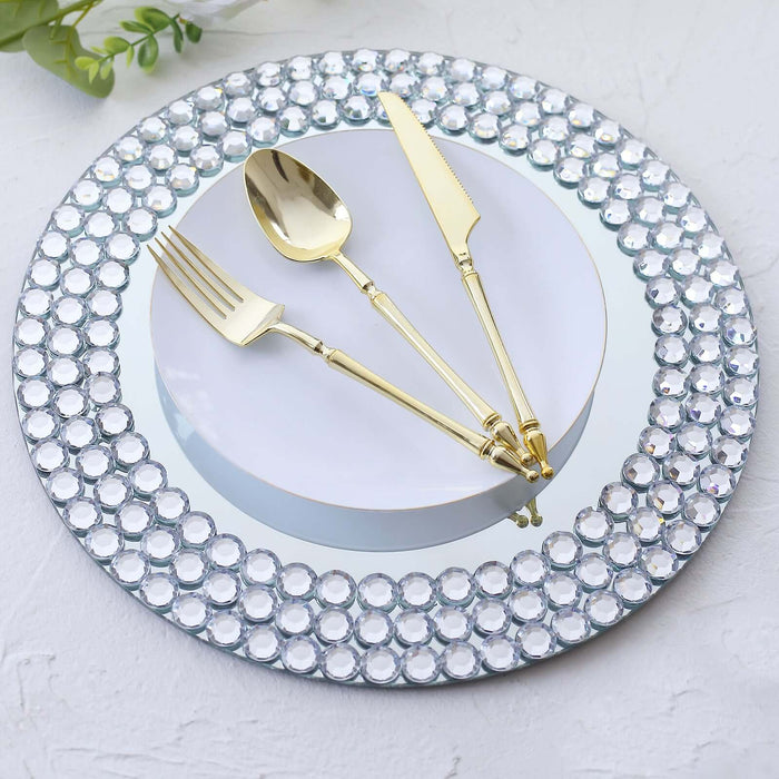 Elegant silver and gold cutlery on a mirrored plate with crystal rim accents.