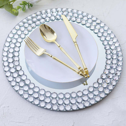 Elegant silver and gold cutlery on a mirrored plate with crystal rim accents.
