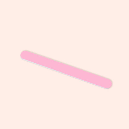 The Manucurist 3-Face Nail Buffer, a single pink tool with rounded edges, rests diagonally on a light beige background—ideal for achieving flawless nails.
