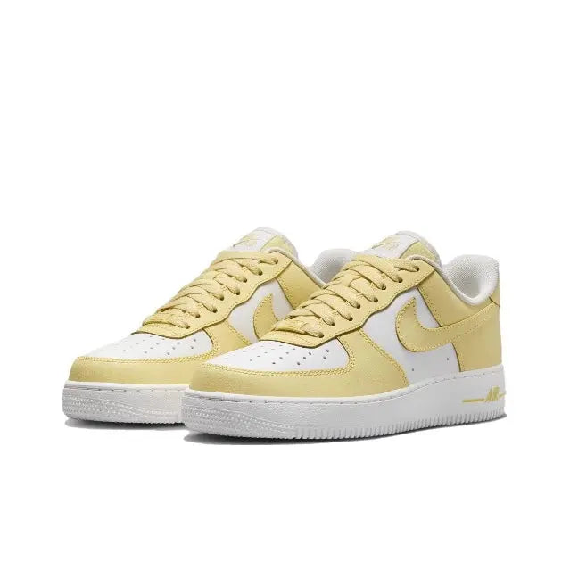 Nike low-top sneakers pair view, pale yellow leather with white side panels and laces