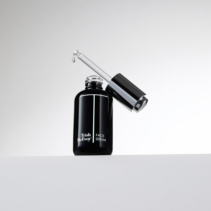 Black face serum bottle with dropper on a white background