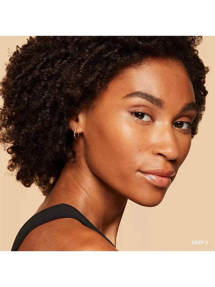 Woman with glowing deep skin tone wearing tinted moisturizer, natural makeup look