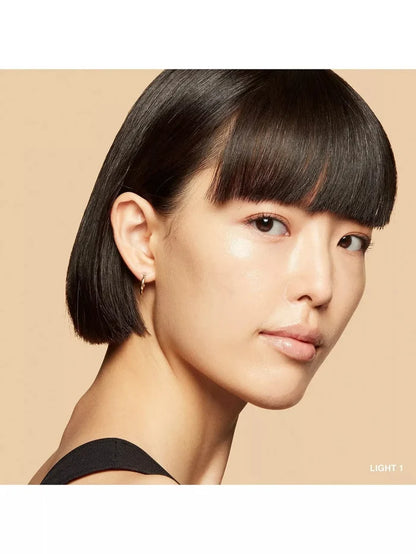 Model wearing skin tint moisturizer in shade Light 1, showing natural, radiant complexion