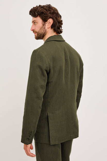 The Bond is a single breasted blazer with two buttons, one chest pocket and two patch pockets in Deep Olive colorway. Back view featured on model.