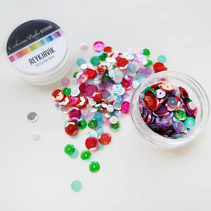 Catherine Pooler - Sequin Mix - Reykjavik. Reykjavík Sequin Mix adds a touch of playful elegance to your holiday projects. This iridescent mix features vibrant red and green sequins with soft pops of pink and icy blue. Available at Embellish Away located in Bowmanville Ontario Canada.