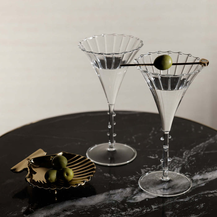 Two martini glasses with olive garnishes on a dark surface.