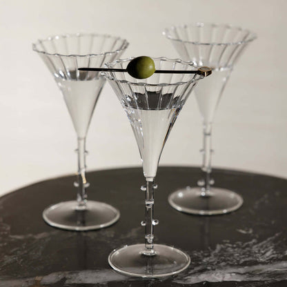 Three martini glasses on a dark surface with a white background