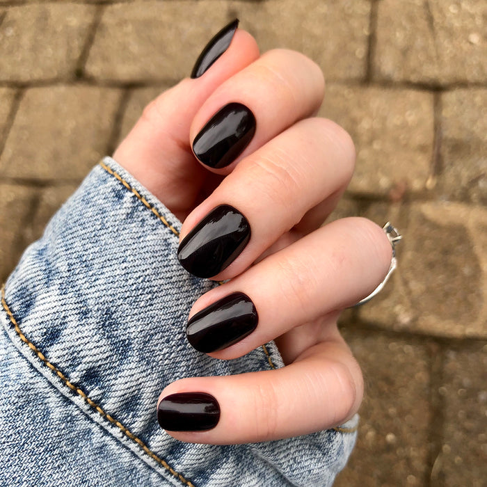Covet | Extra Short | Round - Tab Press-On nails in deep dark plum shade with glossy finish on hand outdoors