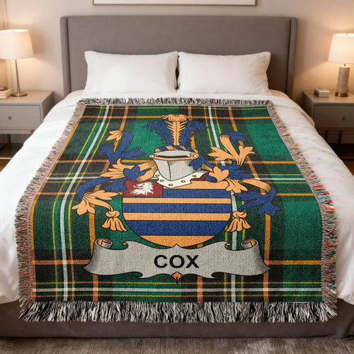 Cox family crest woven blanket laid across a bed.