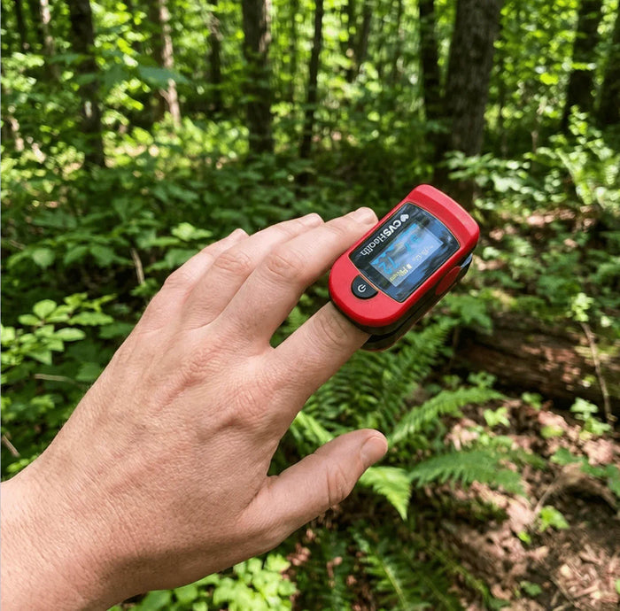 Person using a portable pulse oximeter on finger outdoors in a forest setting