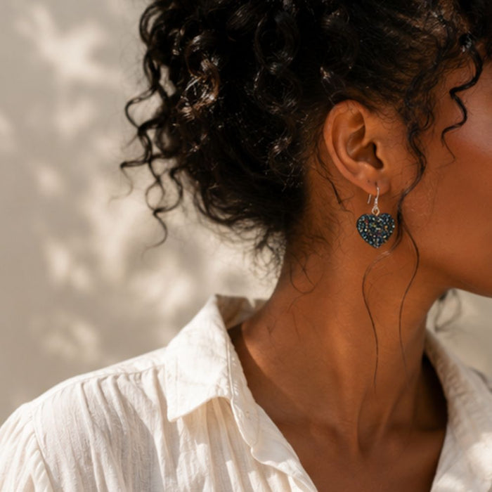Close-up of a person wearing heart-shaped earrings with a blurred background
