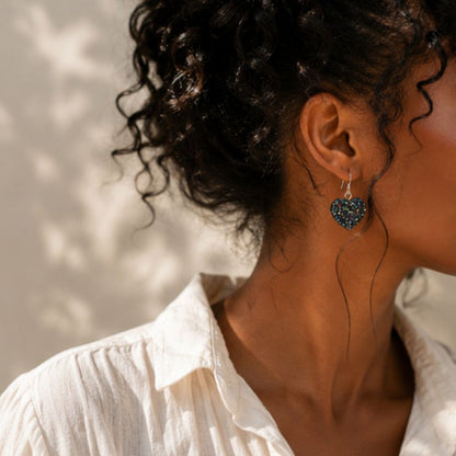 Close-up of a person wearing heart-shaped earrings with a blurred background