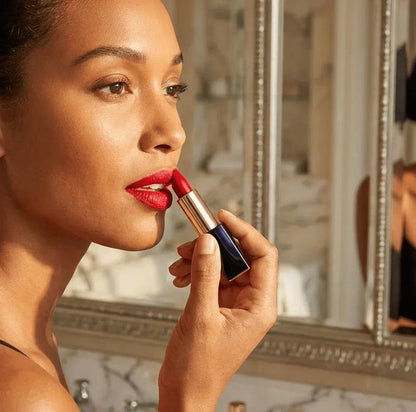 Woman applying red lipstick in front of bathroom mirror, close-up beauty shot