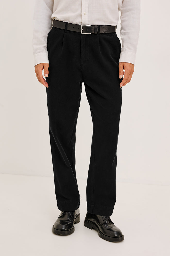 Ezra Pant in Brushed Cotton Twill With Relaxed Fit, Single Front Pleats, Ankle-Length Hem, Zip Fly, Side Pockets, and Back Double-Welt Pockets in Black Colorway - Full Body Front View Featured on Model