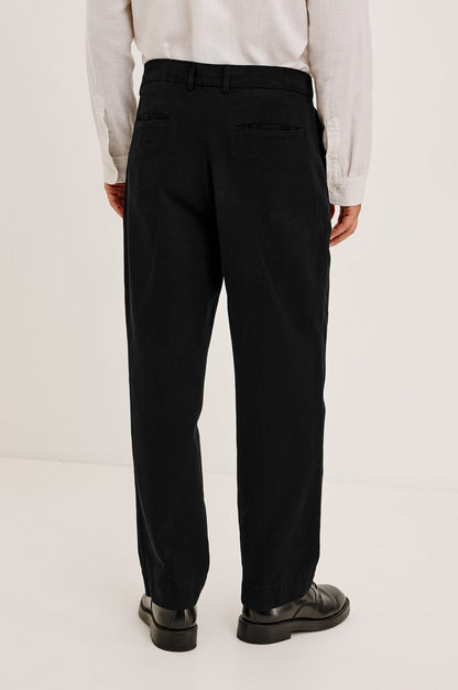 Ezra Pant in Brushed Cotton Twill With Relaxed Fit, Single Front Pleats, Ankle-Length Hem, Zip Fly, Side Pockets, and Back Double-Welt Pockets in Black Colorway - Lower Body Back View Featured on Model
