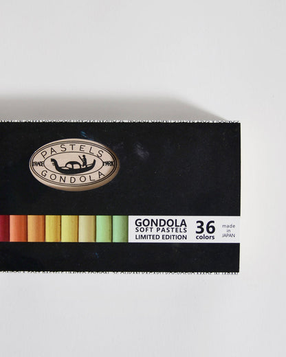 Box of Gondola soft pastels with a black lid and colorful pastels underneath on a gray background