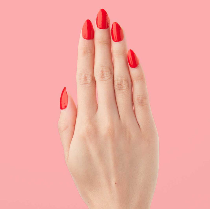 Lava - Press-On | Medium | Almond showing hand with medium almond false nails in vibrant spicy orange red polish on pink background