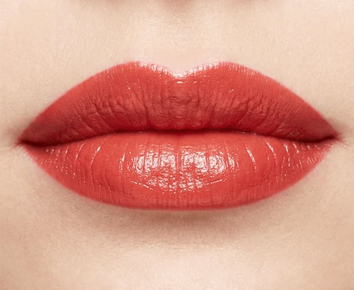 Close-up of lips wearing glossy poppy red lipstick, beauty makeup focus