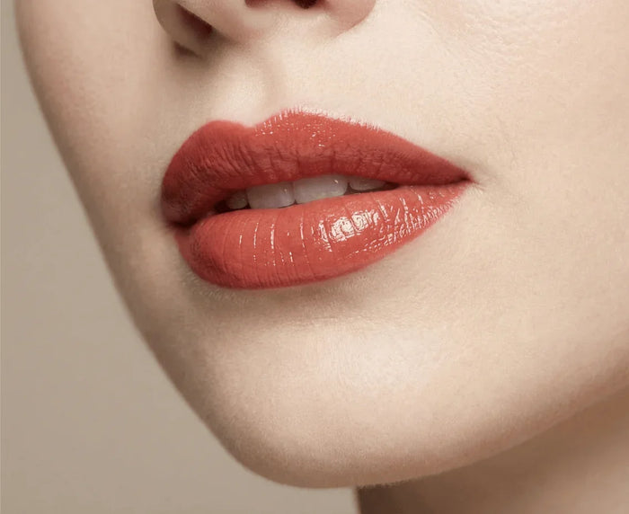Close-up of lips wearing glossy poppy red lipstick, smooth finish, beauty makeup look