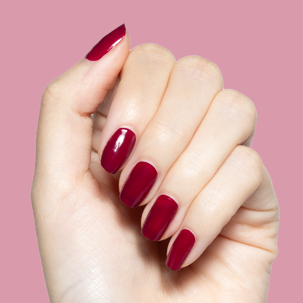 Hand with glossy Mulberry deep plum quick dry gel polish manicure on natural nails against solid mauve background