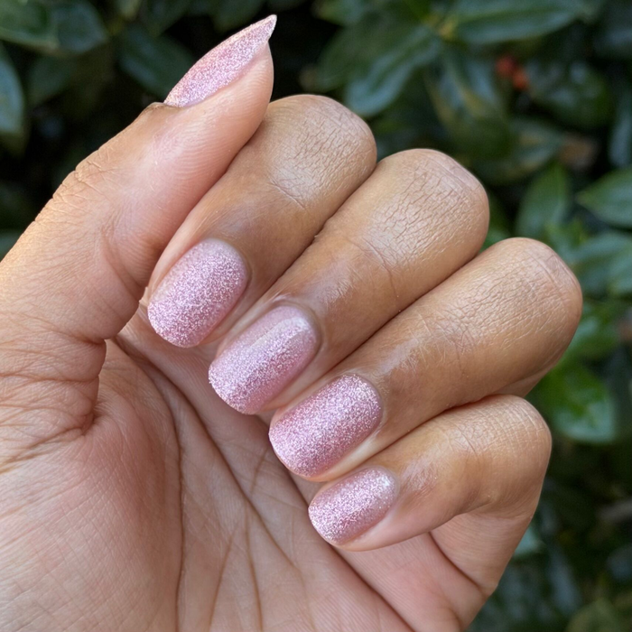 Hand displaying nails with textured pink holographic glitter manicure using MWAH quick dry polish by Olive and June