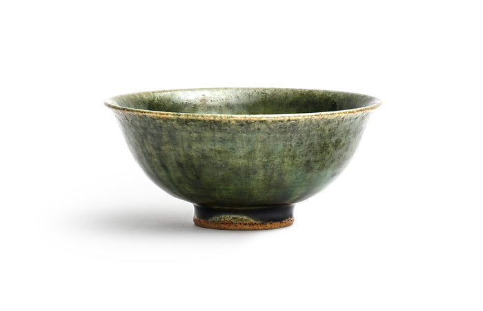 Silhouetted image of ceramic oribe rice bowl with deep green glaze by Time and Style against white background.