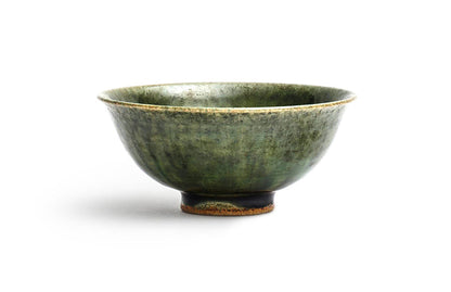 Silhouetted image of ceramic oribe rice bowl with deep green glaze by Time and Style against white background.
