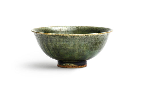 Silhouetted image of ceramic oribe rice bowl with deep green glaze by Time and Style against white background.