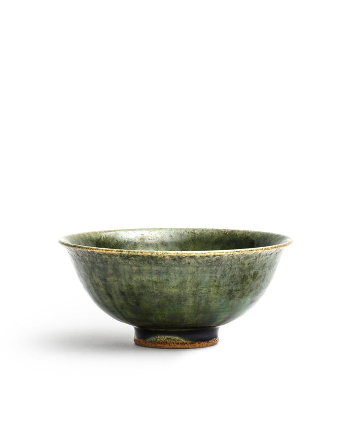 Silhouetted image of ceramic oribe rice bowl with deep green glaze by Time and Style against white background.