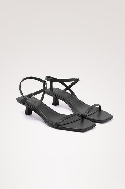 Palma Sandal Heel in Top-Grain Leather With Single Toe Strap, Adjustable Buckled Wrap Ankle Strap, and Low Heel in Black Colorway - angeled frontview of shoe.