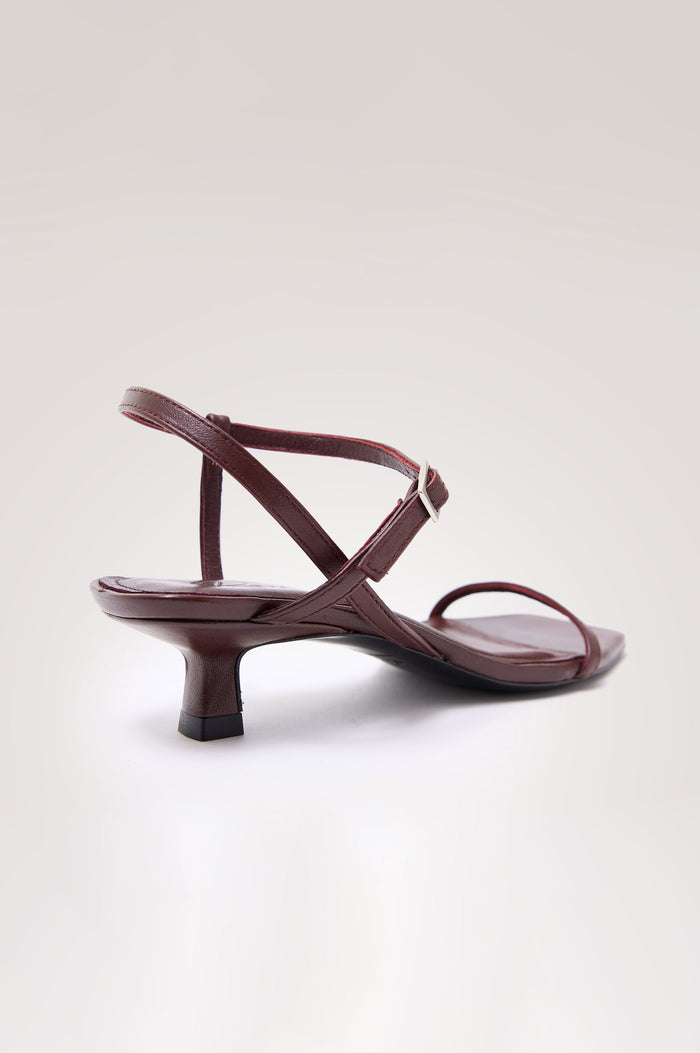 Palma Sandal Heel in Top-Grain Leather With Single Toe Strap, Adjustable Buckled Wrap Ankle Strap, and Low Heel in Burgundy Colorway - angeled back view of shoe.