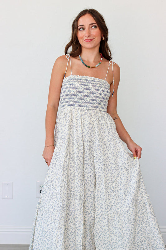 Woman wearing a light blue floral maxi dress against a white background