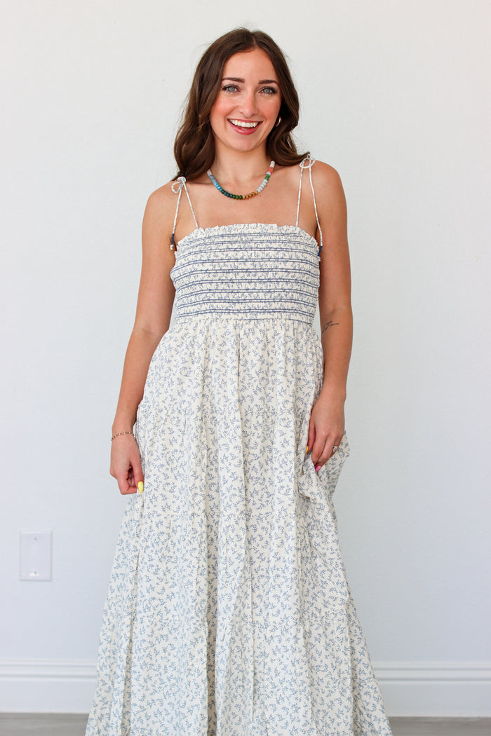 Woman wearing a light blue floral maxi dress against a white background