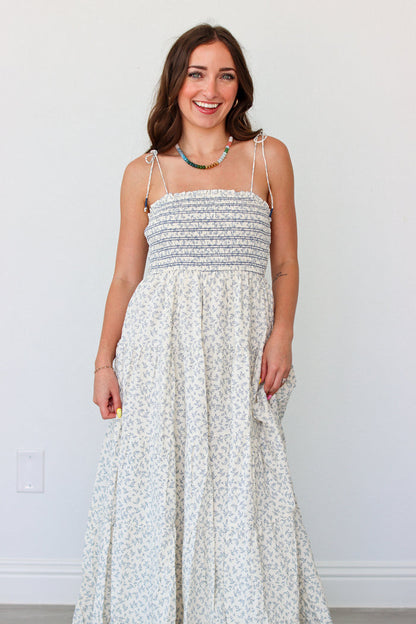 Woman wearing a light blue floral maxi dress against a white background
