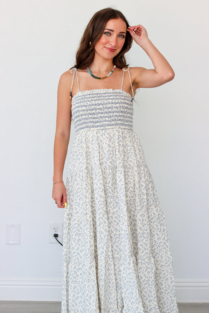 Woman wearing a light blue floral maxi dress against a white background