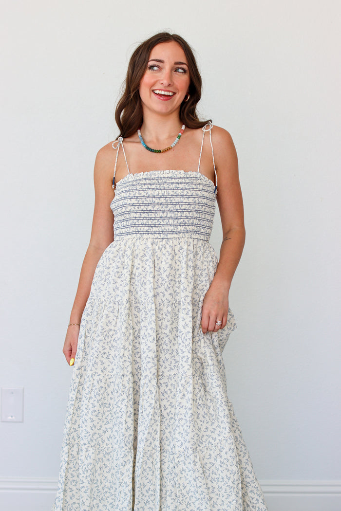 Woman wearing a light blue floral maxi dress against a white background