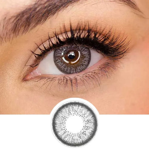 Pink Label Eyelighter Grey color contact lens on top of a dark eye paired with subtle eye makeup and curled wispy eyelashes, above the contact lens design.