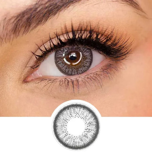 Pink Label Eyelighter Grey color contact lens on top of a dark eye paired with subtle eye makeup and curled wispy eyelashes, above the contact lens design.