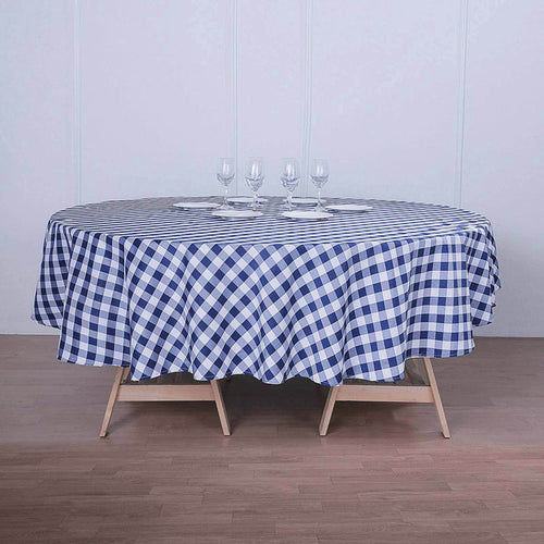 Round blue and white checked tablecloth on a wooden table with glasses.
