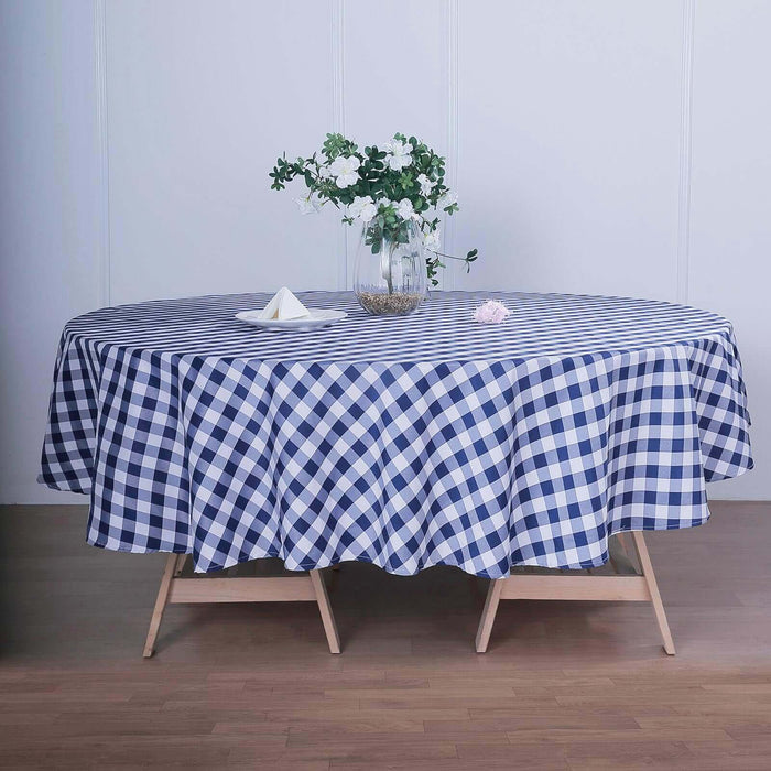 Navy and white gingham tablecloth draped over a round table with floral centerpiece.