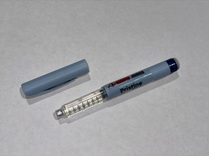 A gray insulin pen lies on a white surface; its cap is removed and rests nearby.