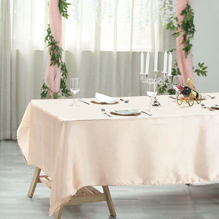 Elegant pink tablecloth draped over a wooden table set for dining.