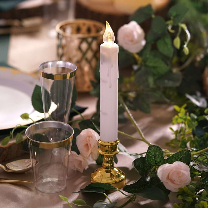 Elegant candle with gold holder, surrounded by roses and glass cups.